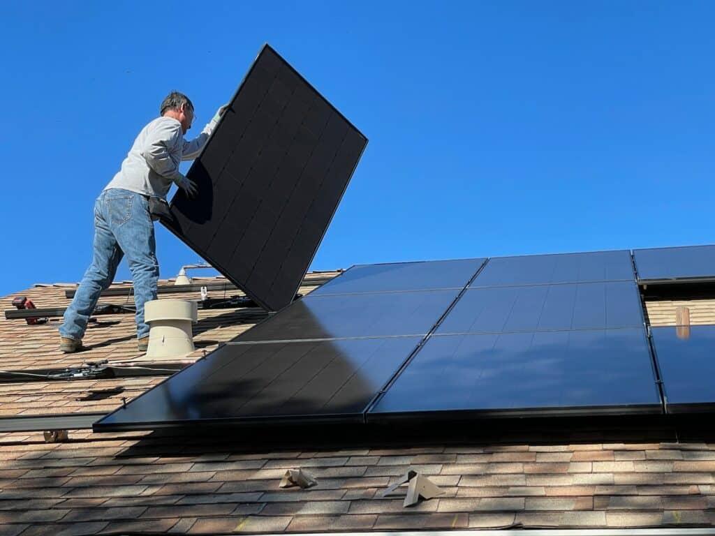 Man installing a solar panel on a roof.