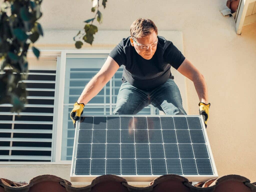Man installing a solar panel on a roof after inspecting it.